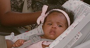 Photo of an infant looking toward the camera over the side of her car seat.