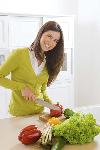 Una mujer cortando verduras.