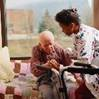 A younger woman assisting an older adult with a walker.