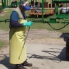 Alguien que lleva un delantal resistente a los productos químicos mientras limpia el equipo de aplicación de pesticidas.