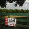 Fence in front of a field with a sign that says, "Sale. 19.2 acres."