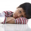 A sad little boy sitting with a glass of milk