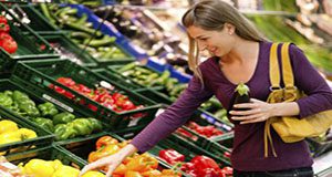 A photo of a woman shopping at a produce stand.